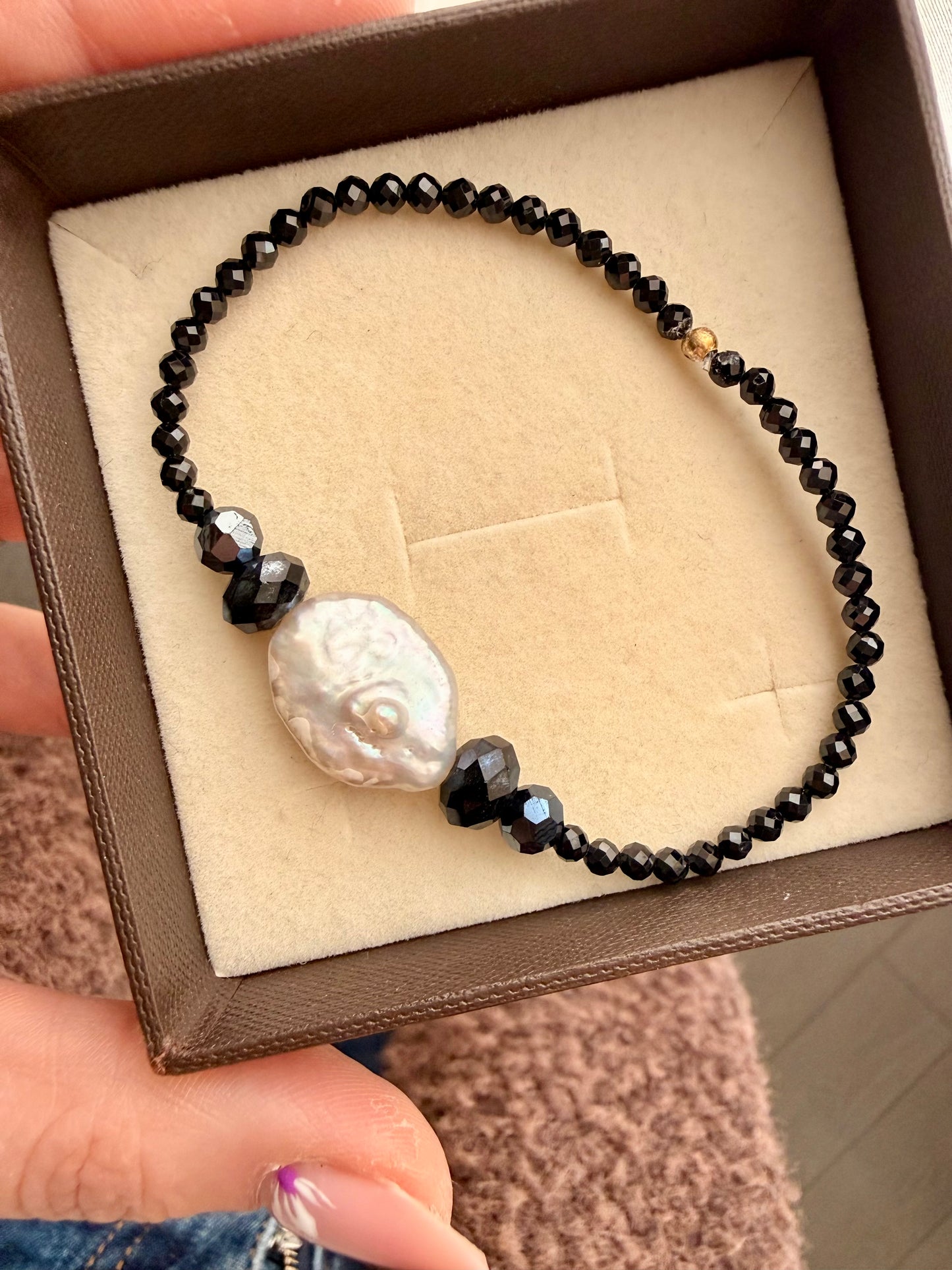 BRACCIALE ELASTICO CON CRISTALLI NERI E SPINELLI CON PERLA NATURALE CENTRALE